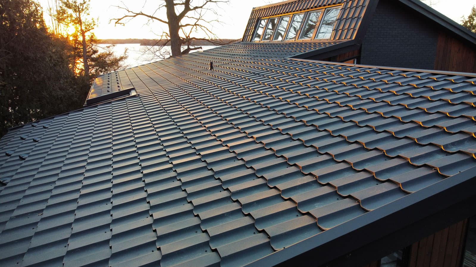 A Rudan metal tile roof at golden hour on a lakeside home